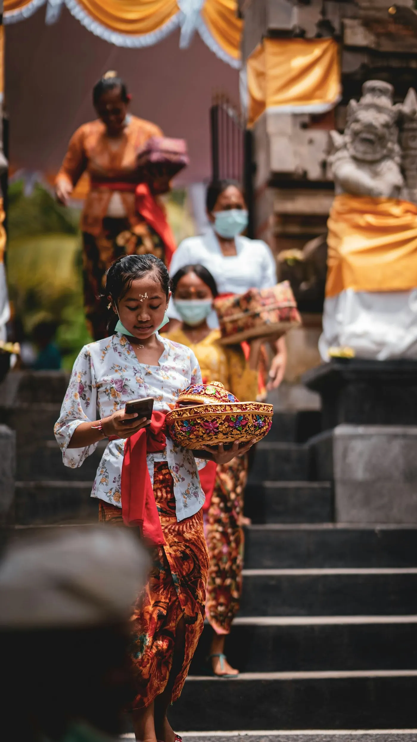 Balinese women in kebaya carrying offerings down temple steps