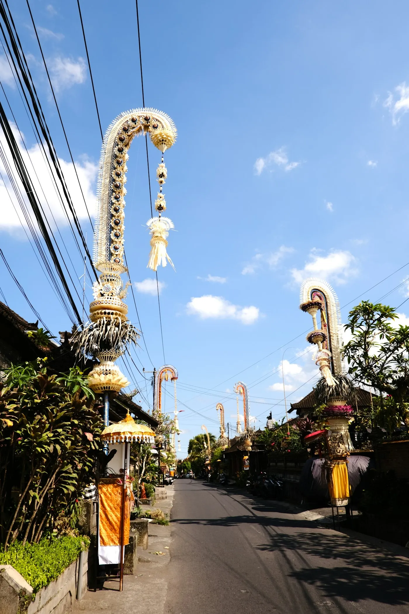 Penjor poles arching over a Balinese village street